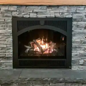 Cozy fireplace with stone surround and burning logs.